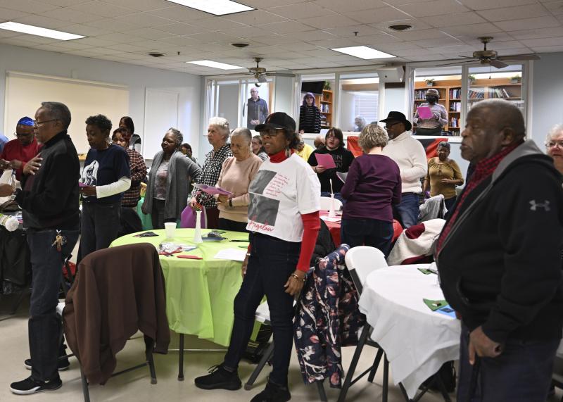 Everyone rises to their feet as the singing of “The Star-Spangled Banner” and the Black national anthem take place.